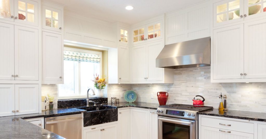 white kitchen cabinet replacements that reach the ceiling with black countertops and sink