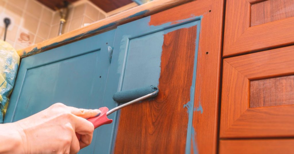 kitchen cabinets being painted blue with a small paint roller